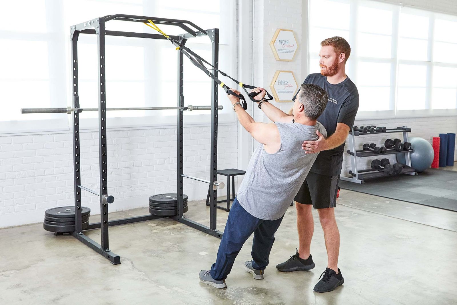 trainer helping client workout on machine